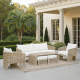 Outdoor patio set with wicker furniture and white cushions on a patio with a pergola and palm trees in the background.